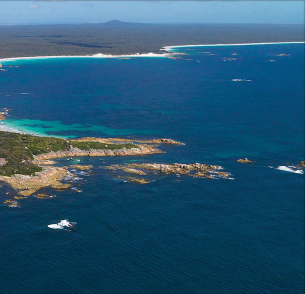 Aerial view of a rugged coastline with turquoise ocean and rocky islands.